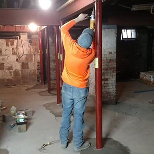 Worker fixes structural beams in basement