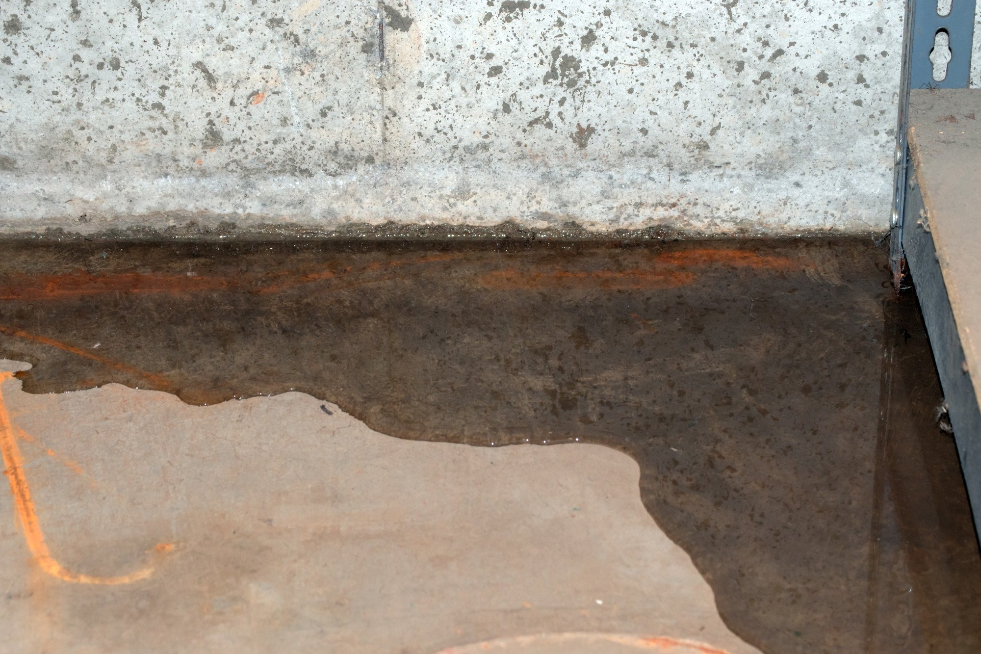 How Long Does Waterproofing Last? - image of basement floor leaking water at the corner where the wall meets the floor.