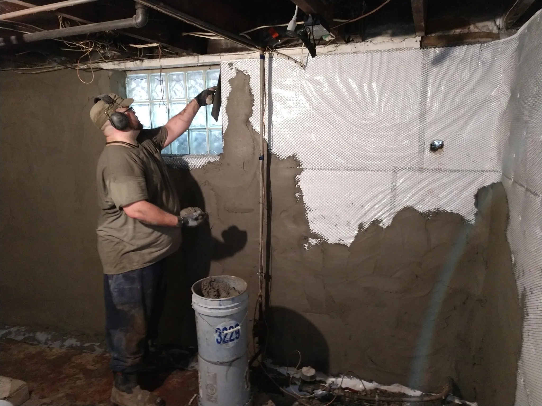 Man working on interior basement waterproofing on walls