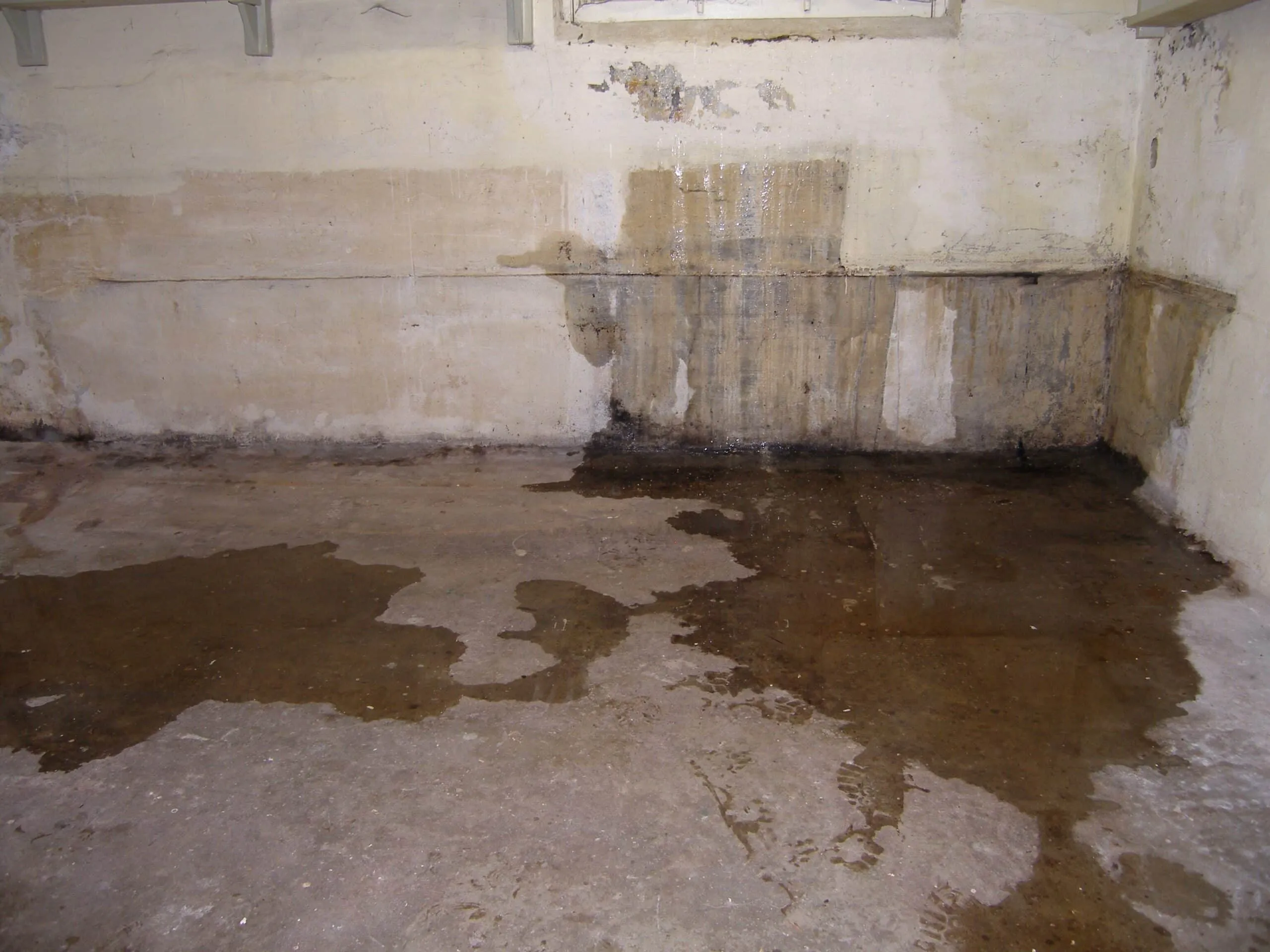 water leak inside a basement on the floor and through cracks in the walls